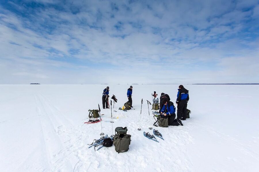 Lapland: Ice Fishing, Floating & BBQ Snow Adventure - Ice fishing on a frozen lake: cutting the hole and setting expectations